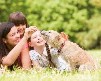 Mother and daughters in park with dog smiling