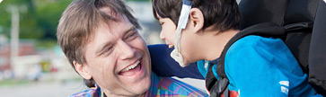 father laughing with son in wheelchair