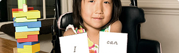 girls sitting at desk holding up an I can sign