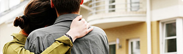 couple on front lawn looking at home