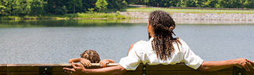 dad and son sitting on a bench looking at the pond